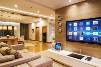 Modern living room interior with a large TV screen displaying a home automation system.